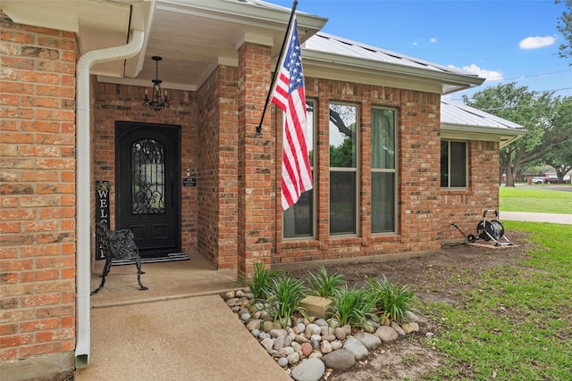 view of exterior entry featuring metal roof and brick siding