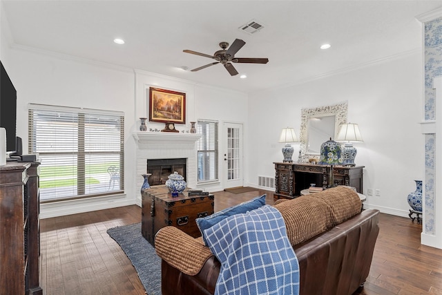 living area with visible vents, a ceiling fan, dark wood-style floors, and a brick fireplace