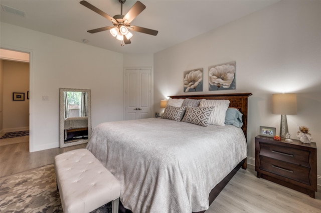bedroom featuring visible vents, a closet, baseboards, light wood-type flooring, and a ceiling fan