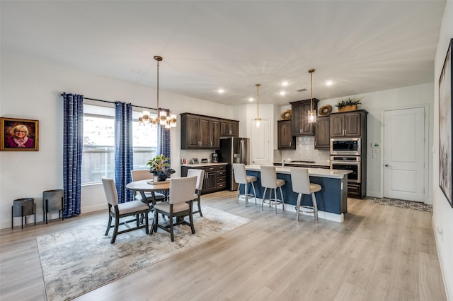 dining space featuring baseboards, recessed lighting, a notable chandelier, and light wood finished floors