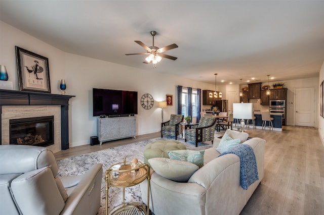 living area with light wood-style floors, ceiling fan, baseboards, recessed lighting, and a fireplace