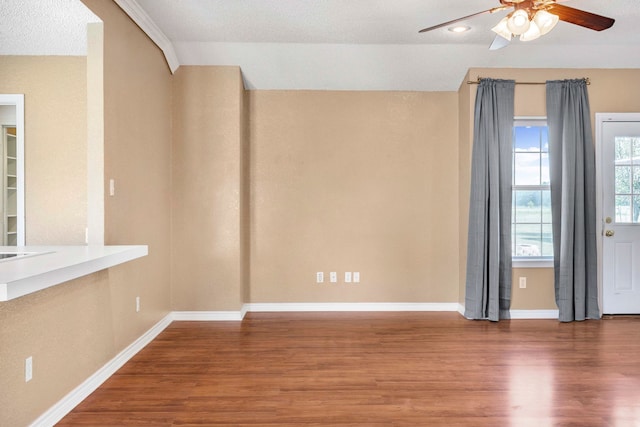 spare room featuring wood finished floors, a ceiling fan, and baseboards