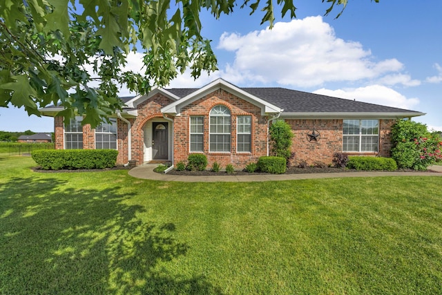 ranch-style house with a front lawn, a shingled roof, and brick siding