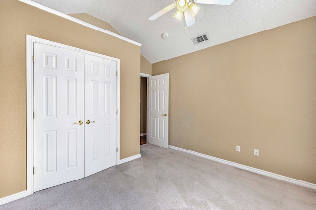 unfurnished bedroom with visible vents, a closet, baseboards, vaulted ceiling, and light carpet