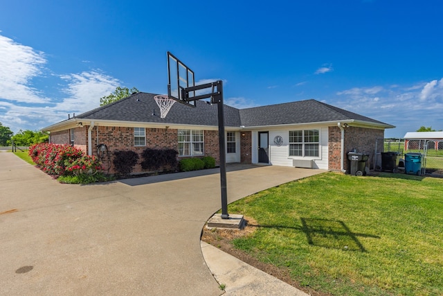 view of front of house featuring a front lawn, fence, roof with shingles, and brick siding