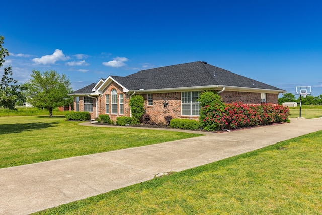 single story home with brick siding, a front yard, and roof with shingles