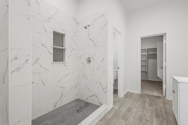 bathroom featuring a shower stall, toilet, vanity, a walk in closet, and wood finish floors