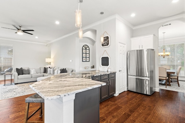 kitchen featuring dark wood-style flooring, arched walkways, freestanding refrigerator, a peninsula, and visible vents