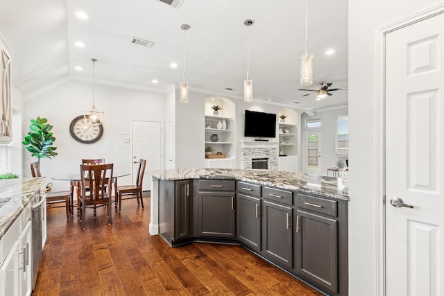 kitchen featuring visible vents, light stone countertops, a stone fireplace, dark wood-type flooring, and a ceiling fan