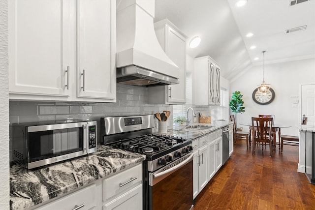 kitchen with visible vents, premium range hood, tasteful backsplash, vaulted ceiling, and stainless steel appliances