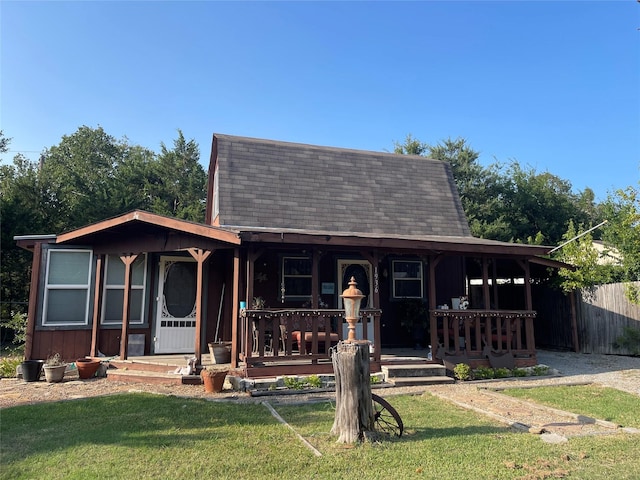 view of front of property with fence, covered porch, and a front yard