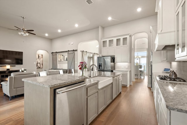 kitchen with arched walkways, backsplash, appliances with stainless steel finishes, and a sink