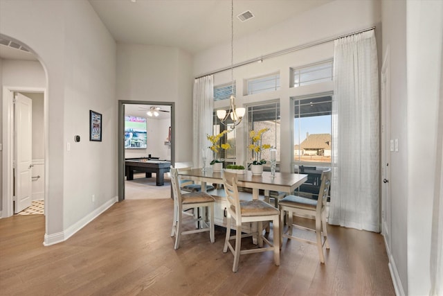 dining area with baseboards, visible vents, wood finished floors, and arched walkways