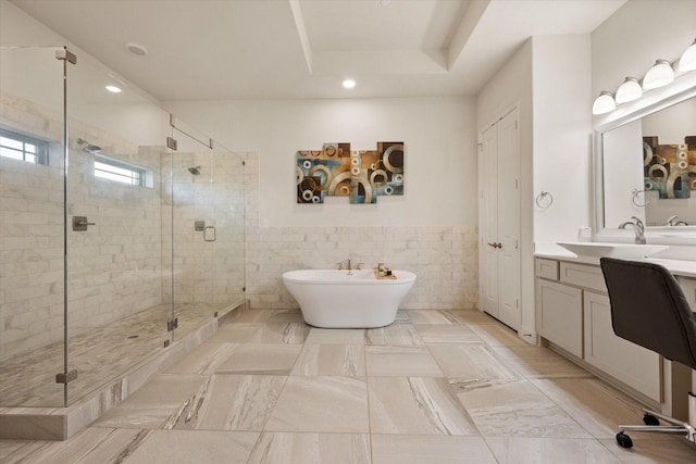 full bath with tile walls, vanity, a stall shower, and a soaking tub