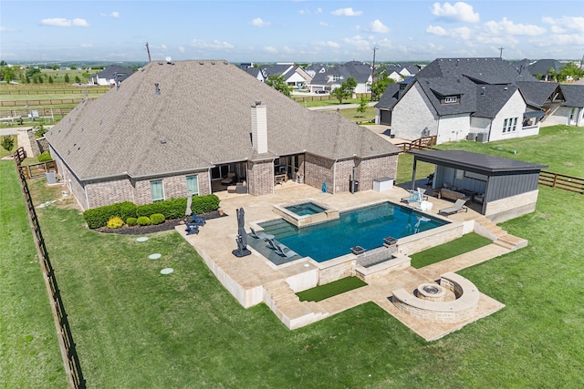 view of swimming pool with a pool with connected hot tub, a patio, a lawn, and a fenced backyard