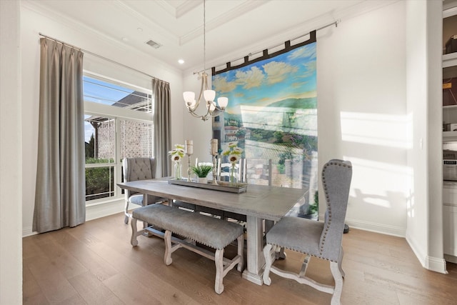 dining room with visible vents, ornamental molding, a notable chandelier, and wood finished floors