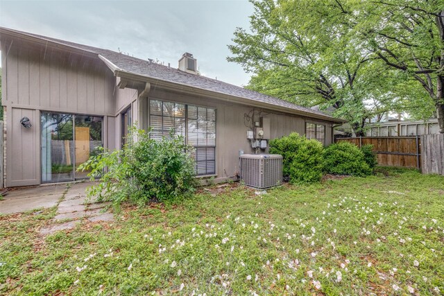 2406 Sutton Dr, Arlington, TX 76018 - rear view of property featuring a yard, fence, cooling unit, and a chimney