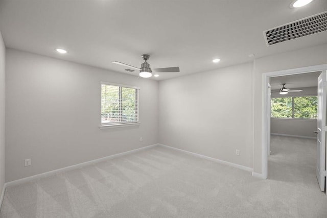 unfurnished room with ceiling fan, a healthy amount of sunlight, light colored carpet, and visible vents