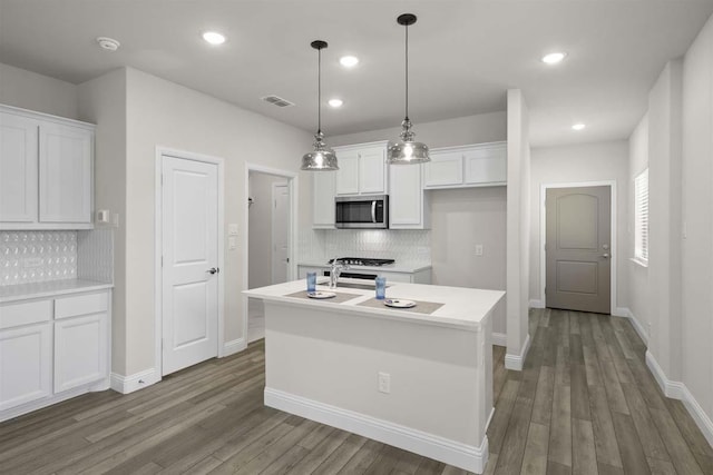 kitchen with white cabinets, wood finished floors, backsplash, and stainless steel microwave