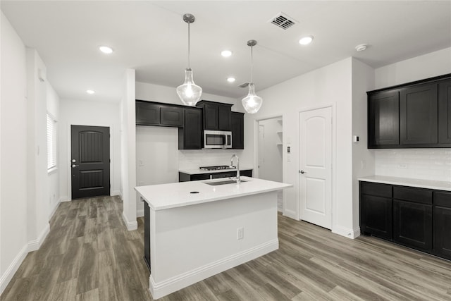 202 Griffith, Princeton, TX 75407 - kitchen with stainless steel microwave, light wood-style flooring, backsplash, a sink, and baseboards