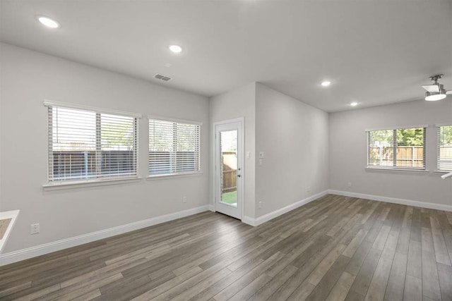 spare room with wood finished floors, visible vents, and baseboards