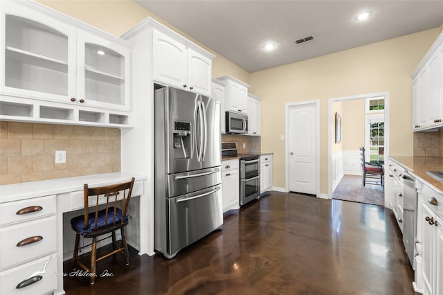 kitchen featuring concrete floors, white cabinets, stainless steel appliances, and decorative backsplash