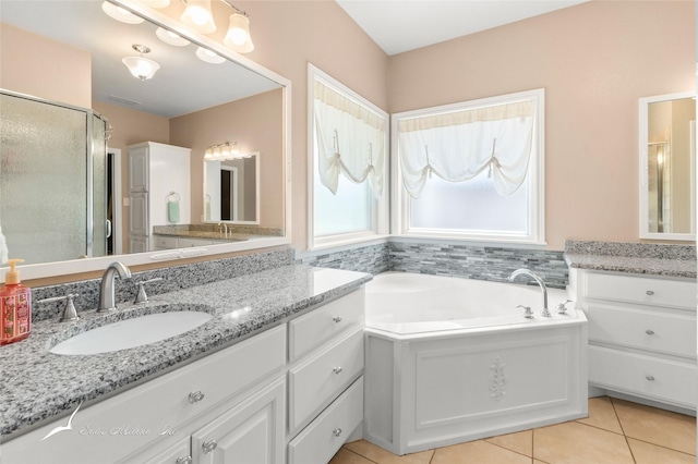 bathroom featuring a sink, a shower stall, two vanities, a garden tub, and tile patterned flooring