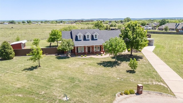 view of front of property with a porch, a front yard, brick siding, roof with shingles, and fence