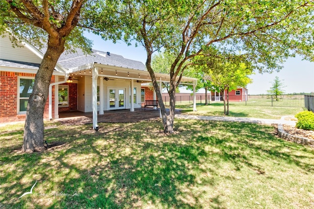 view of yard featuring a patio, ceiling fan, french doors, and a fenced backyard
