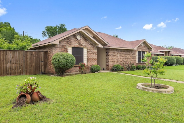 single story home featuring brick siding, fence, and a front lawn