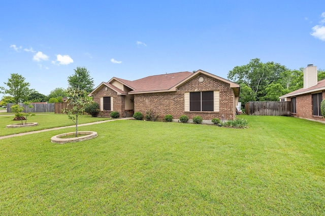 ranch-style house with fence, a front yard, a shingled roof, and brick siding