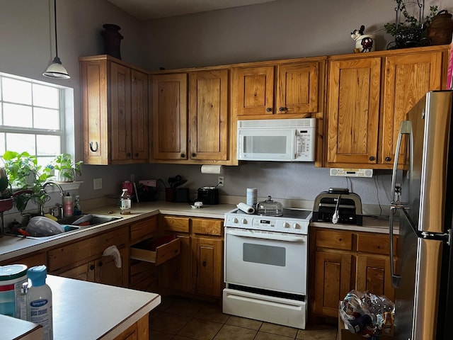 kitchen with a sink, brown cabinetry, and white appliances