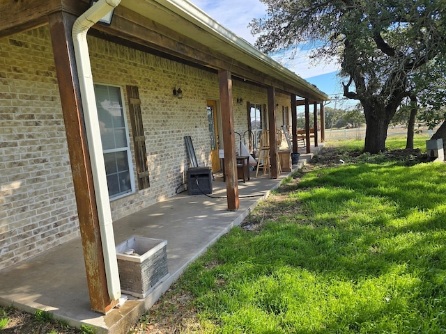 view of home's exterior featuring a yard, brick siding, and a patio area
