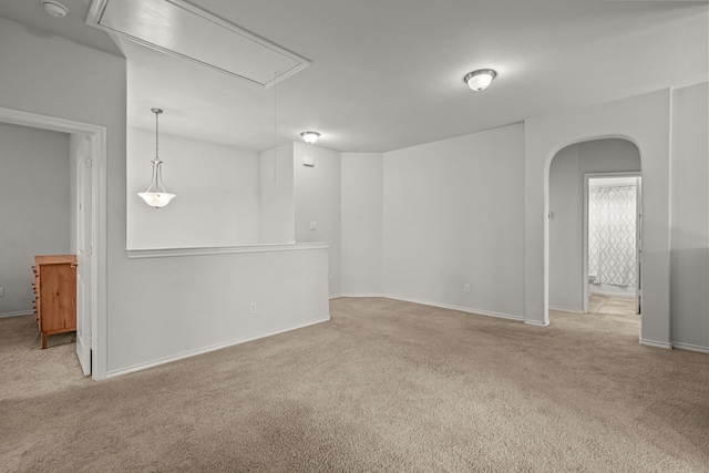 unfurnished room featuring attic access, arched walkways, and carpet