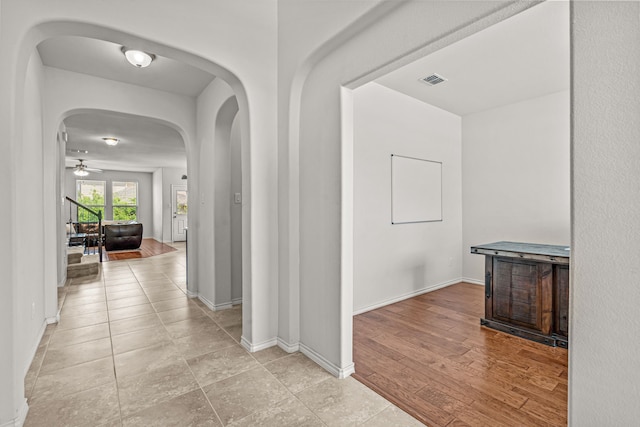 corridor with baseboards, visible vents, and arched walkways