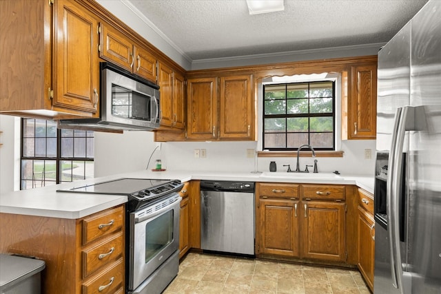 kitchen featuring a textured ceiling, a sink, stainless steel appliances, light countertops, and brown cabinetry