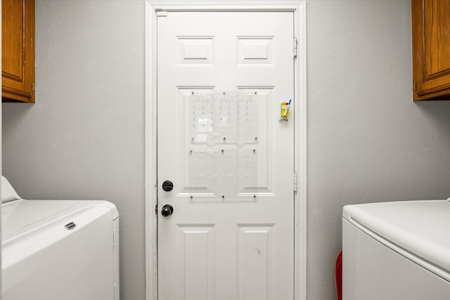 laundry area with separate washer and dryer and cabinet space