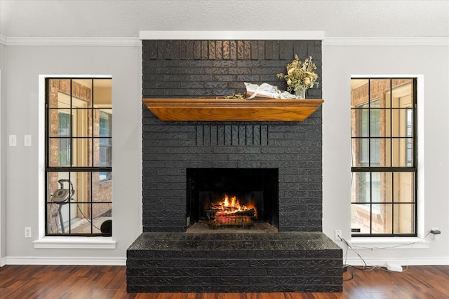 interior details featuring crown molding, a fireplace, wood finished floors, and baseboards