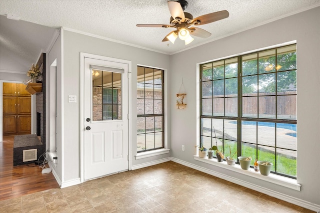doorway with a textured ceiling, ceiling fan, and crown molding