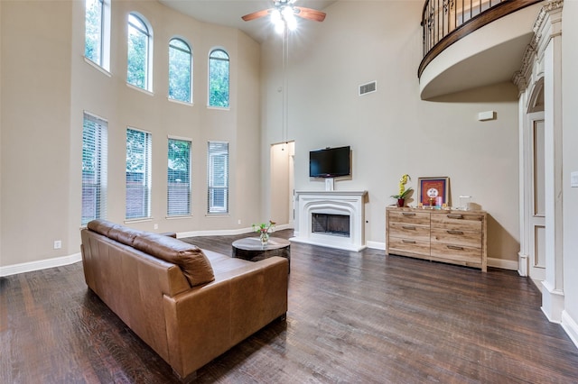 751 Chateaus Dr, Coppell, TX 75019 - living area with visible vents, a high ceiling, dark wood-type flooring, a fireplace with raised hearth, and a ceiling fan