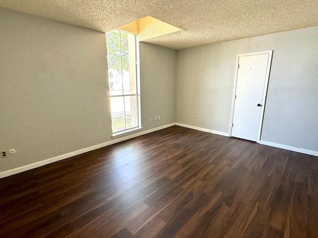 unfurnished room featuring a textured ceiling, plenty of natural light, dark wood finished floors, and baseboards