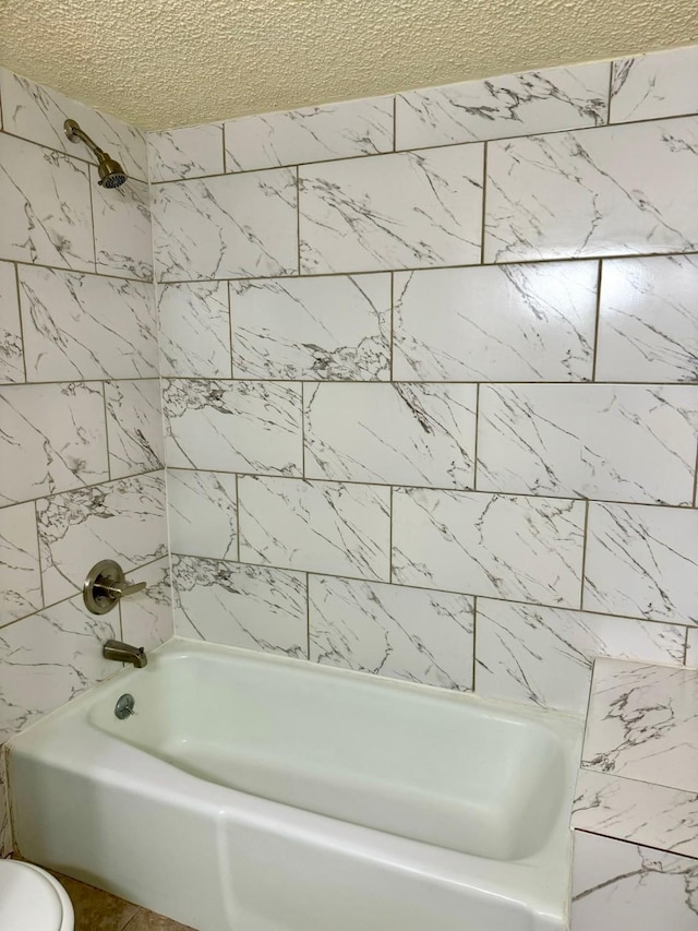 bathroom with toilet, a textured ceiling, and washtub / shower combination