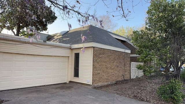 view of home's exterior featuring concrete driveway, a shingled roof, a garage, and brick siding