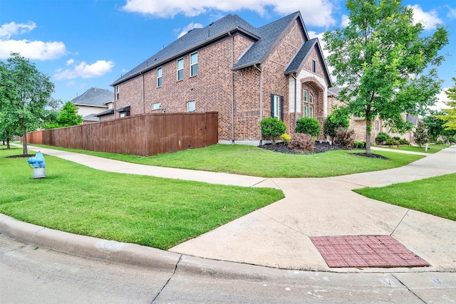 12810 Avanti Dr, Frisco, TX 75035 - view of home's exterior with a yard, brick siding, fence, and a shingled roof