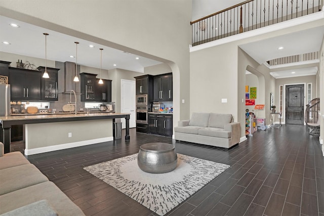 12810 Avanti Dr, Frisco, TX 75035 - living room with a high ceiling, arched walkways, a glass covered fireplace, baseboards, and dark wood-style floors