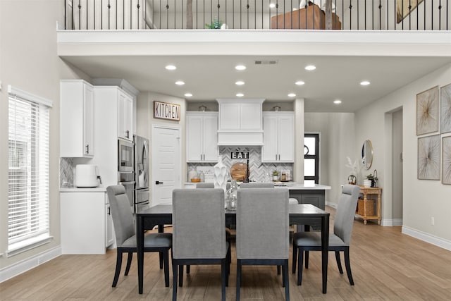 dining area featuring light wood-style floors, a healthy amount of sunlight, visible vents, and baseboards