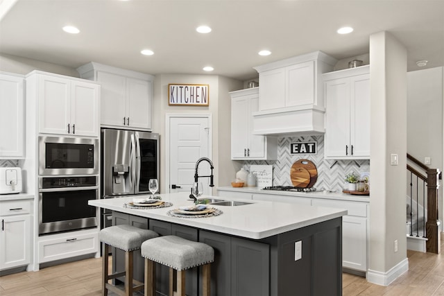kitchen featuring a sink, tasteful backsplash, light countertops, white cabinets, and appliances with stainless steel finishes