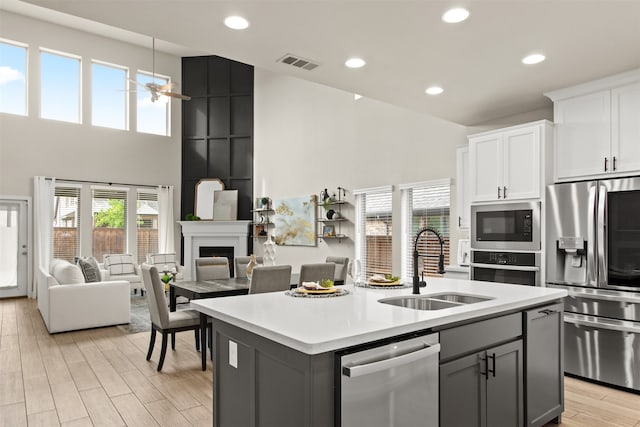 kitchen with a sink, appliances with stainless steel finishes, visible vents, a ceiling fan, and a high ceiling