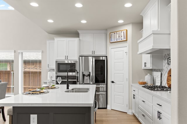 kitchen with recessed lighting, stainless steel appliances, light countertops, a sink, and light wood-type flooring