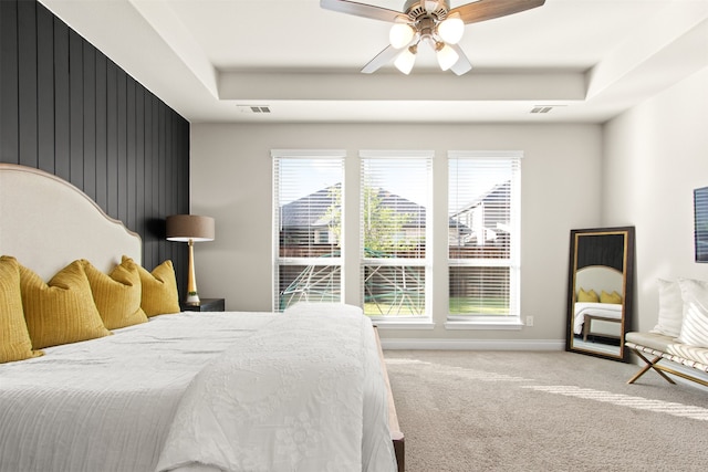 carpeted bedroom featuring visible vents, multiple windows, and a tray ceiling